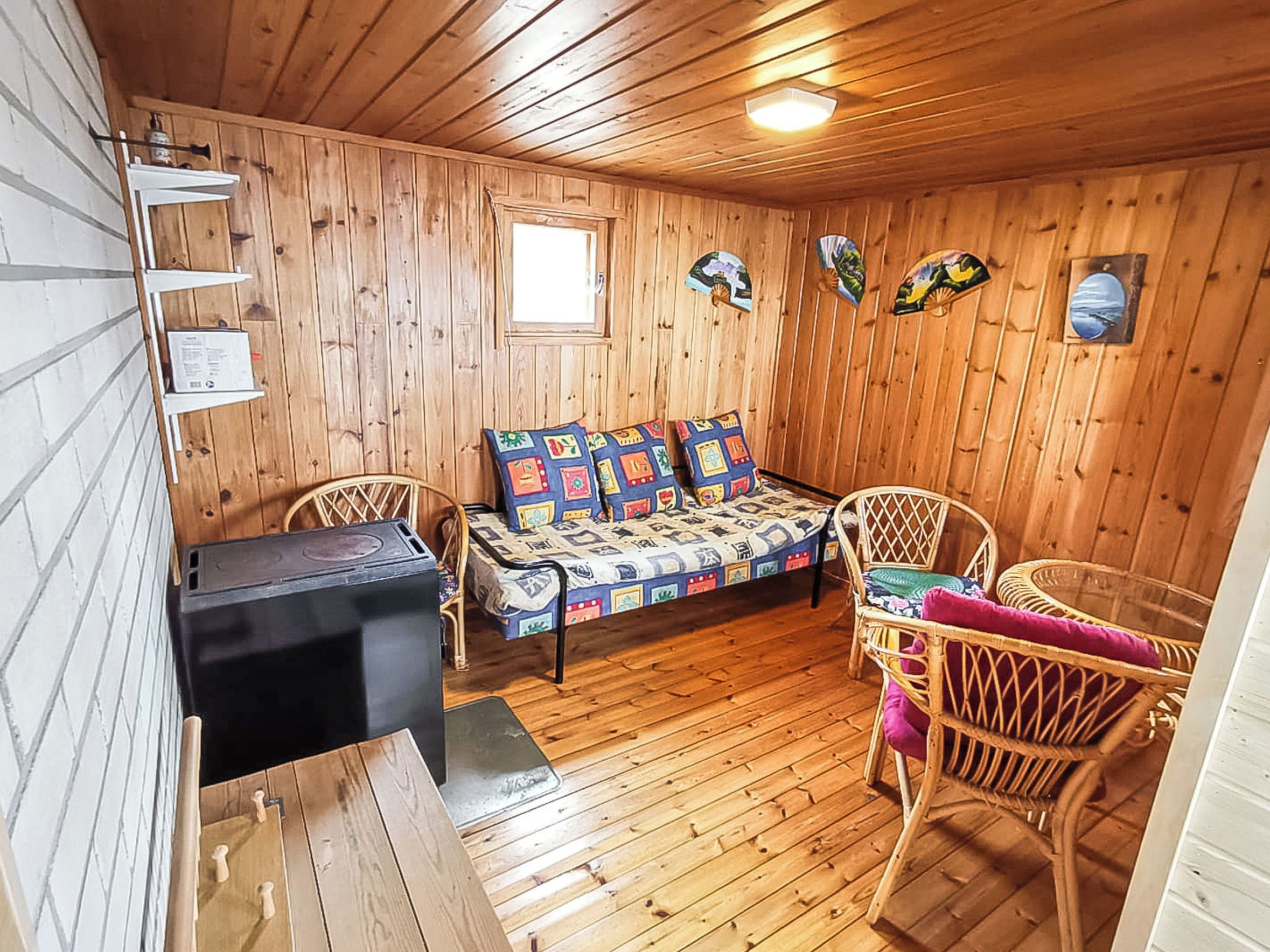 Interno di una baita in legno con un divano, due poltrone in vimini, un tavolino e un termosifone nero.