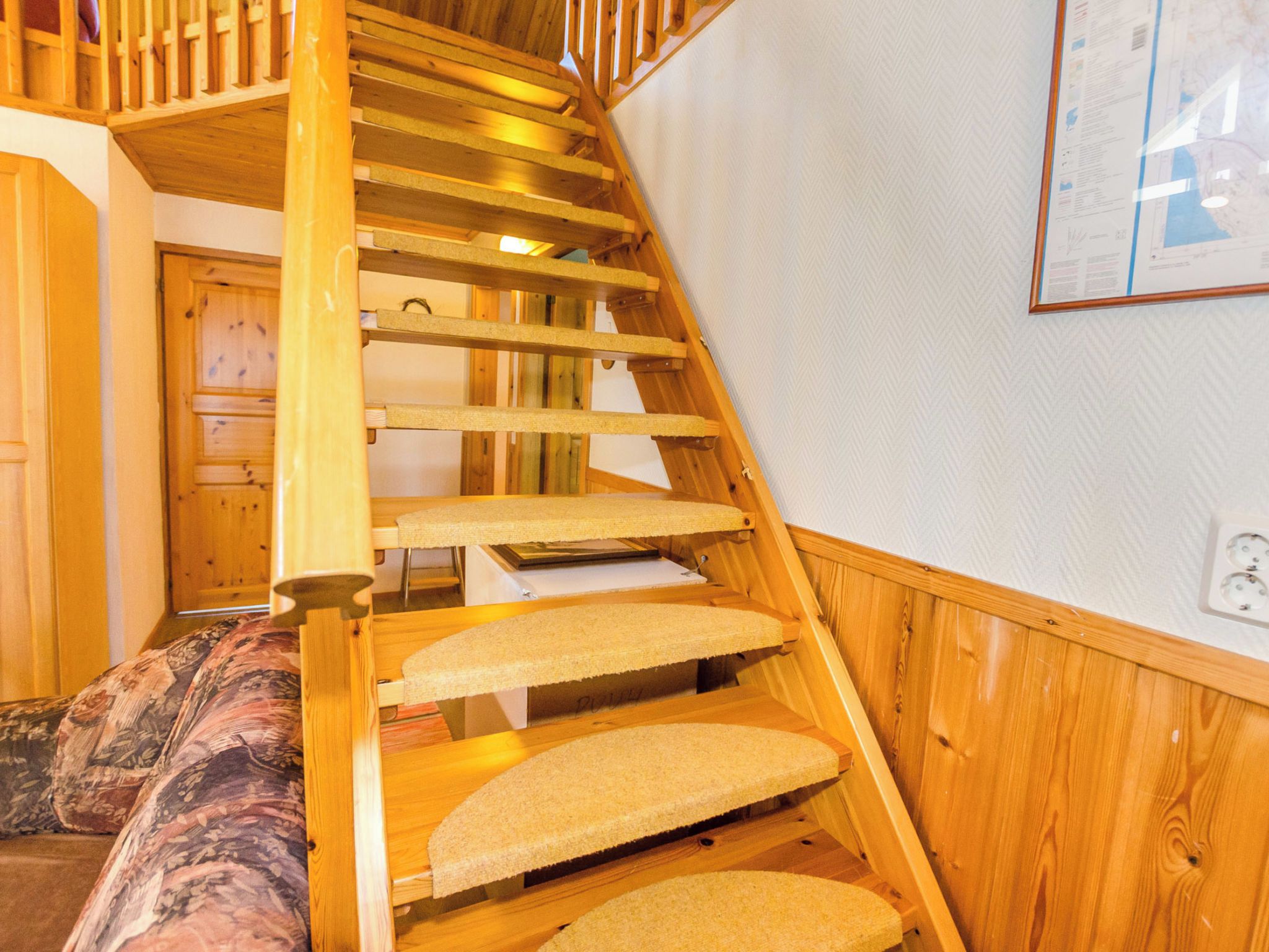Un escalier en bois, dont les marches sont recouvertes de moquette, mène à un palier.