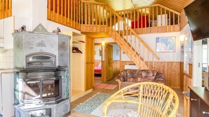 A cozy interior with a stone fireplace, wooden staircase, and wicker furniture. - Uniranta by Interhome (Juuka)