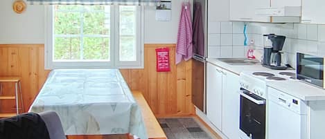Una cocina con una mesa de madera, una estufa, un lavamanos y un ventanal con vistas al verdor.
