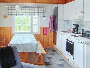 A kitchen with a wooden table, a stove, a sink, and a window with a view of greenery. - Uniranta by Interhome (Juuka)