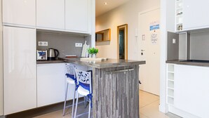 Een moderne keuken met witte kasten, een houten kookeiland en twee barstoelen.