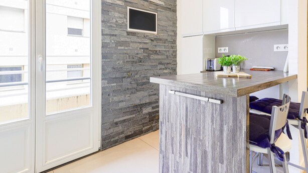 Een moderne keuken met een betegelde achterwand, een ingebouwde televisie en een klein kookeiland met een plant.