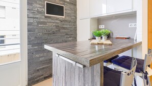 Een moderne keuken met een stenen muur, een ingebouwde televisie en een houten aanrecht.