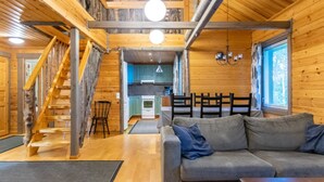 A cozy cabin interior with a wooden staircase, a living area with a sofa, a kitchen, and a dining area. - Runoniekka by Interhome (Rautalampi)