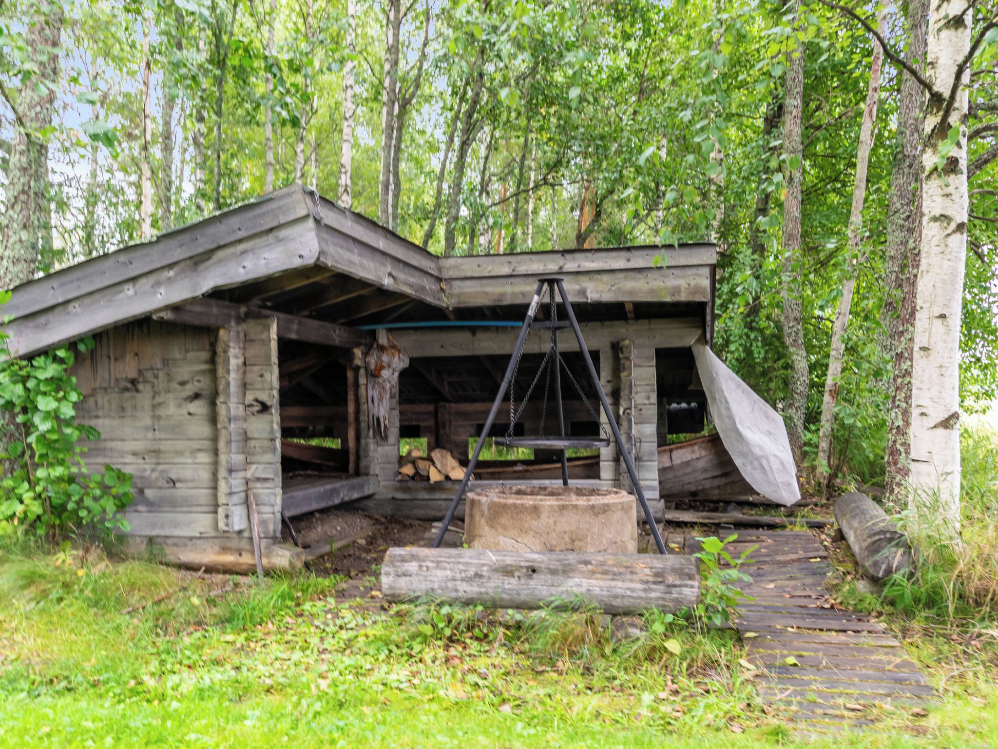 A rustic wooden cabin with a slanted roof, a porch, and a swing hanging from the front.