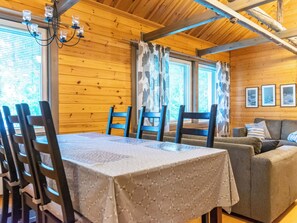 Ein Holzblockhaus-Innenraum mit einem Esstisch, Stühlen, einer Couch und einem Kronleuchter.