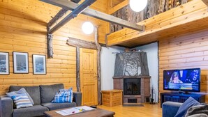 A cozy cabin interior with a wooden ceiling, a fireplace, a television, and a sofa. - Runoniekka by Interhome (Rautalampi)