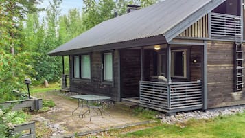 A cabin with a sloped roof, large windows, and a covered porch area.