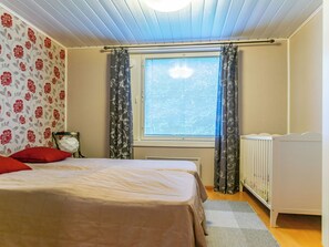 Ein Schlafzimmer mit Bett, Heizkörper, Vorhängen und einem Fenster mit Jalousien.