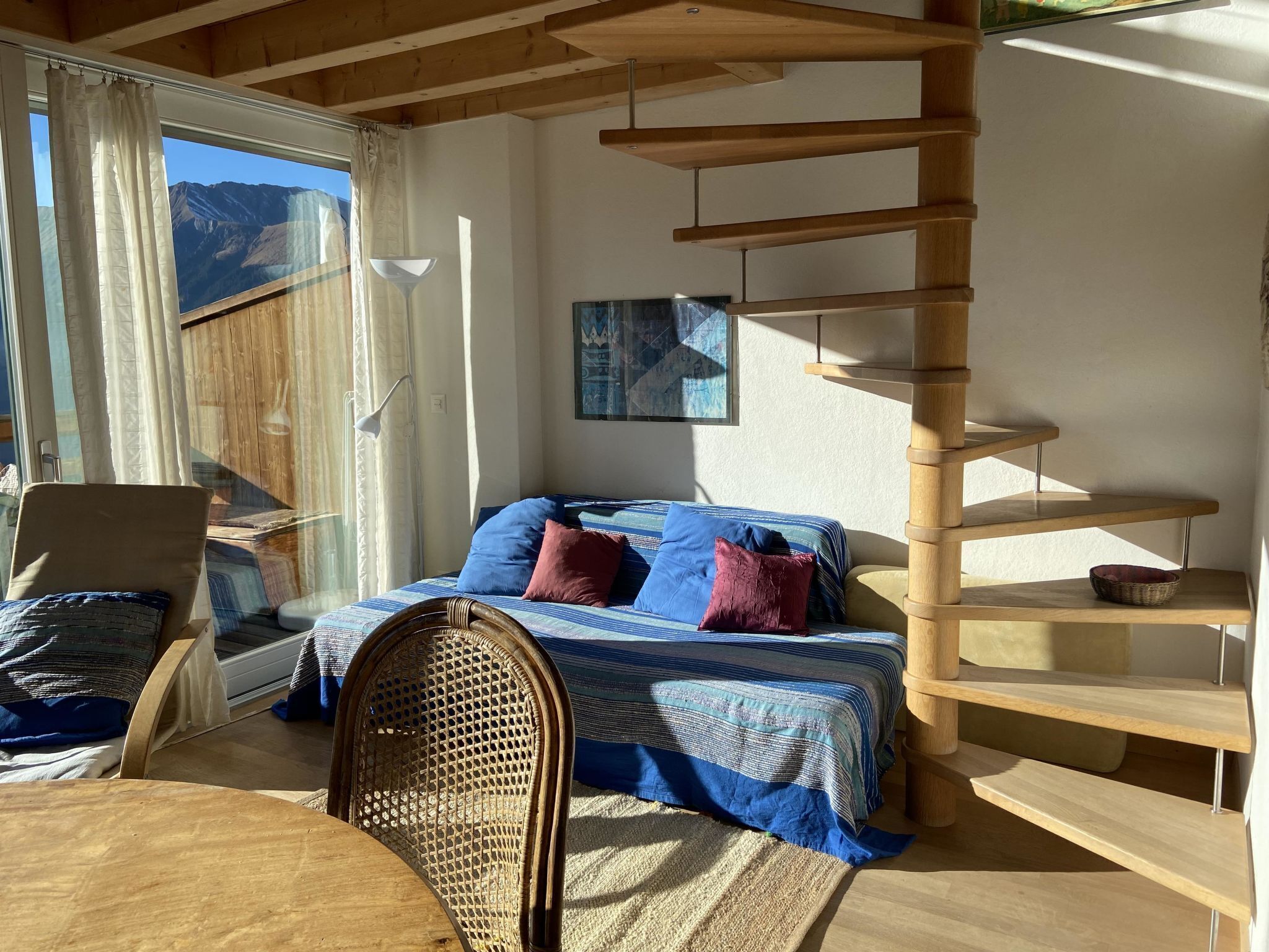 Ein Zimmer mit einem Bett, einem Sessel, einem Tisch und einer Holzspirale.