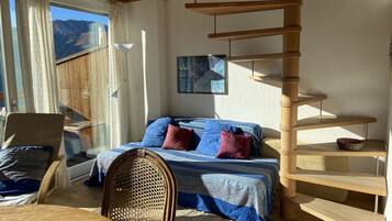 Ein Zimmer mit einem Bett, einem Sessel, einem Tisch und einer Holzspirale.