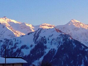 Un paysage de montagne avec des sommets enneigés et un bâtiment au premier plan.