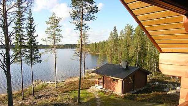 A cabin with a view of a lake surrounded by trees.