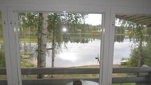 Une pièce dotée d’une grande fenêtre donnant sur un lac, d’une table en bois et d’une chaise.