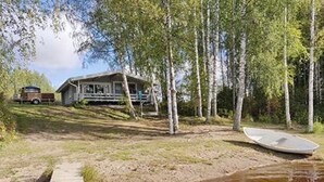 Une cabane avec un quai s’avançant dans une étendue d’eau boueuse, entourée d’arbres.