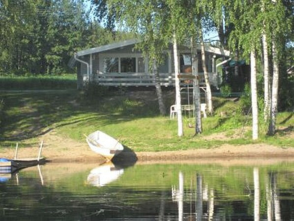 Una cabaña junto al lago con un muelle y un bote.