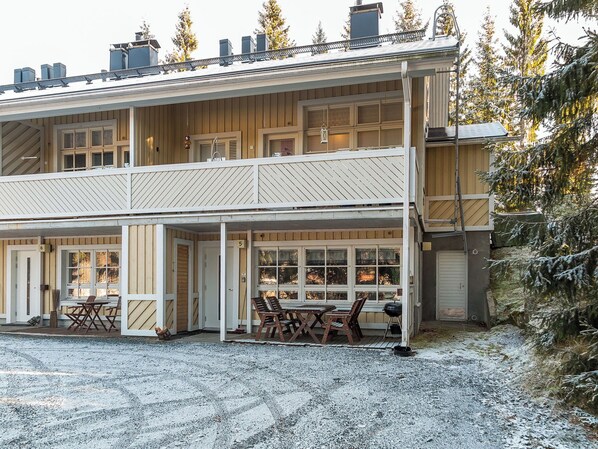 A two-story wooden building with a covered porch and a gravel driveway. - Tahkontilhi e 5 by Interhome (Nilsiä)