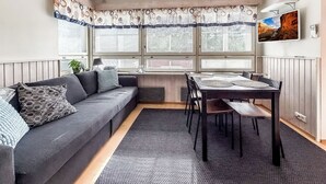 Ein gemütliches Zimmer mit einer Couch, einem Esstisch und großen Fenstern.