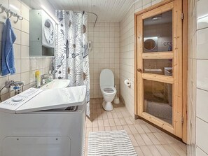 A bathroom with a toilet, sink, shower curtain, and wooden door. - Tahkontilhi e 5 by Interhome (Nilsiä)