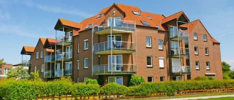 A multi-story residential building with balconies, brick exterior, and a well-maintained lawn.