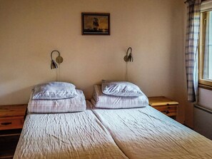 Ein Zimmer mit zwei Betten, jedes mit Kissen und Kopfteil. Darüber an der Wand hängt ein Gemälde.