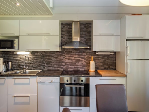 Una cocina moderna con armarios blancos, estufa de acero inoxidable, horno empotrado y microondas.