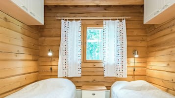 A cabin room with two beds, a small desk, and a window with curtains.