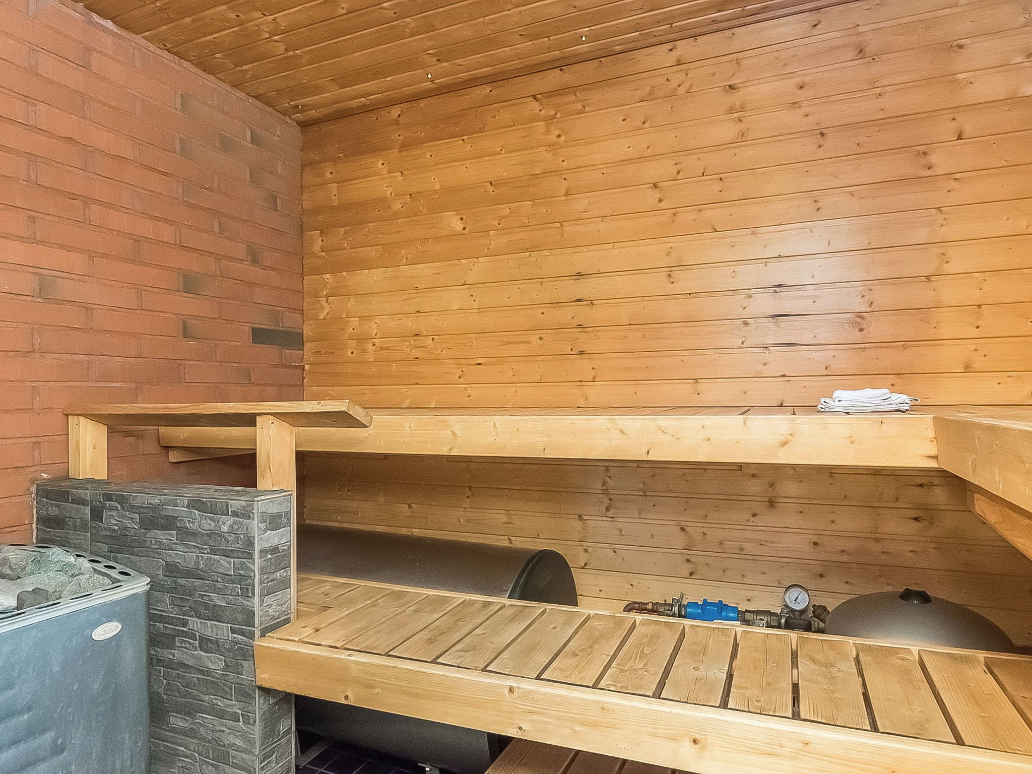 Sauna, jossa on puiset lauteet ja kiviseinä.