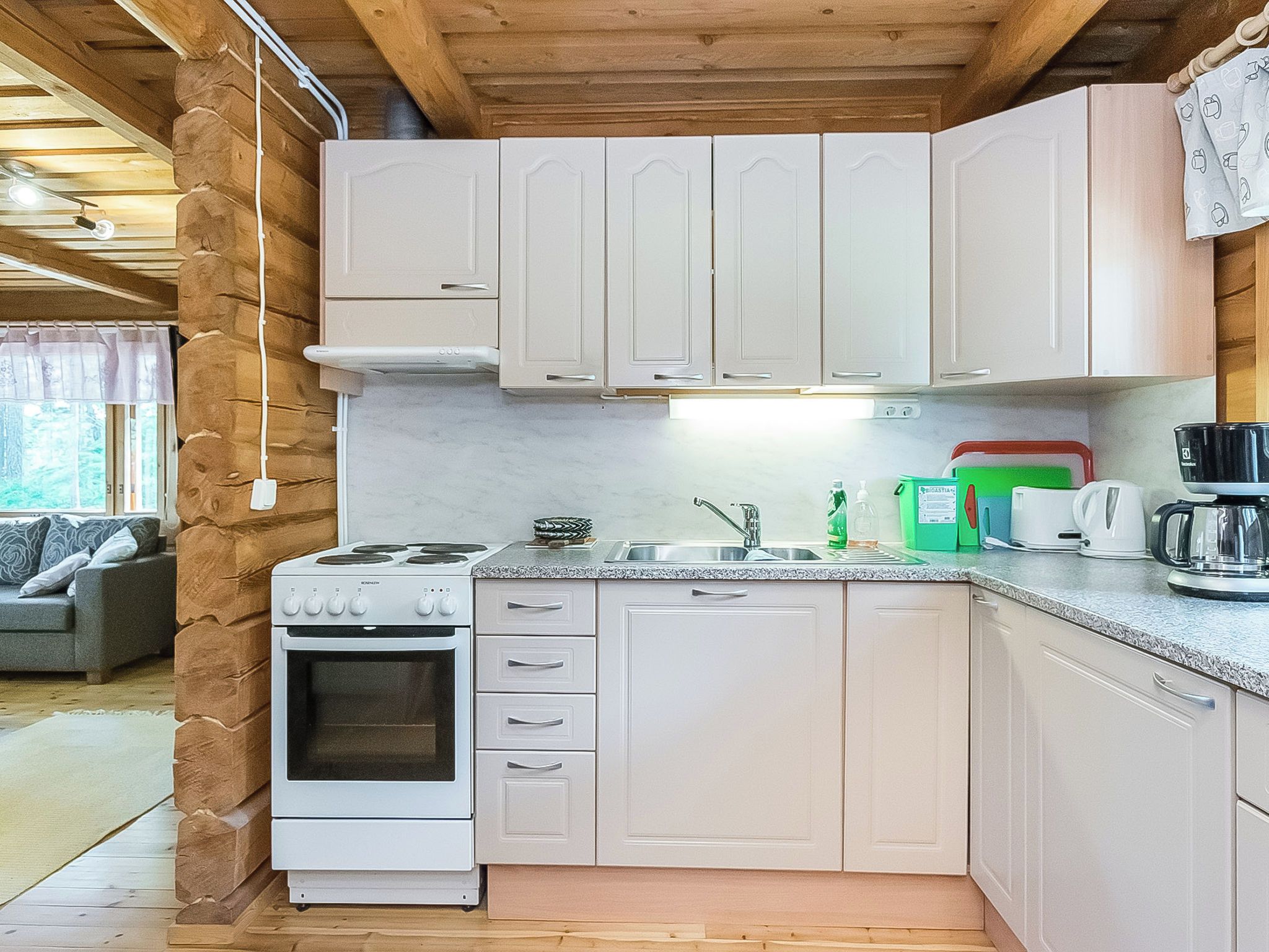 A compact kitchen with white cabinets, a stove, and a sink.