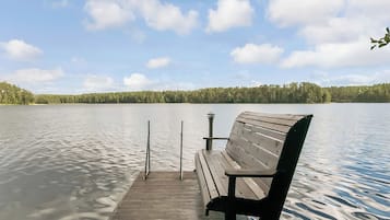 Een houten steiger met een bank die uitsteekt in een kalm meer, omgeven door een bebost oever.