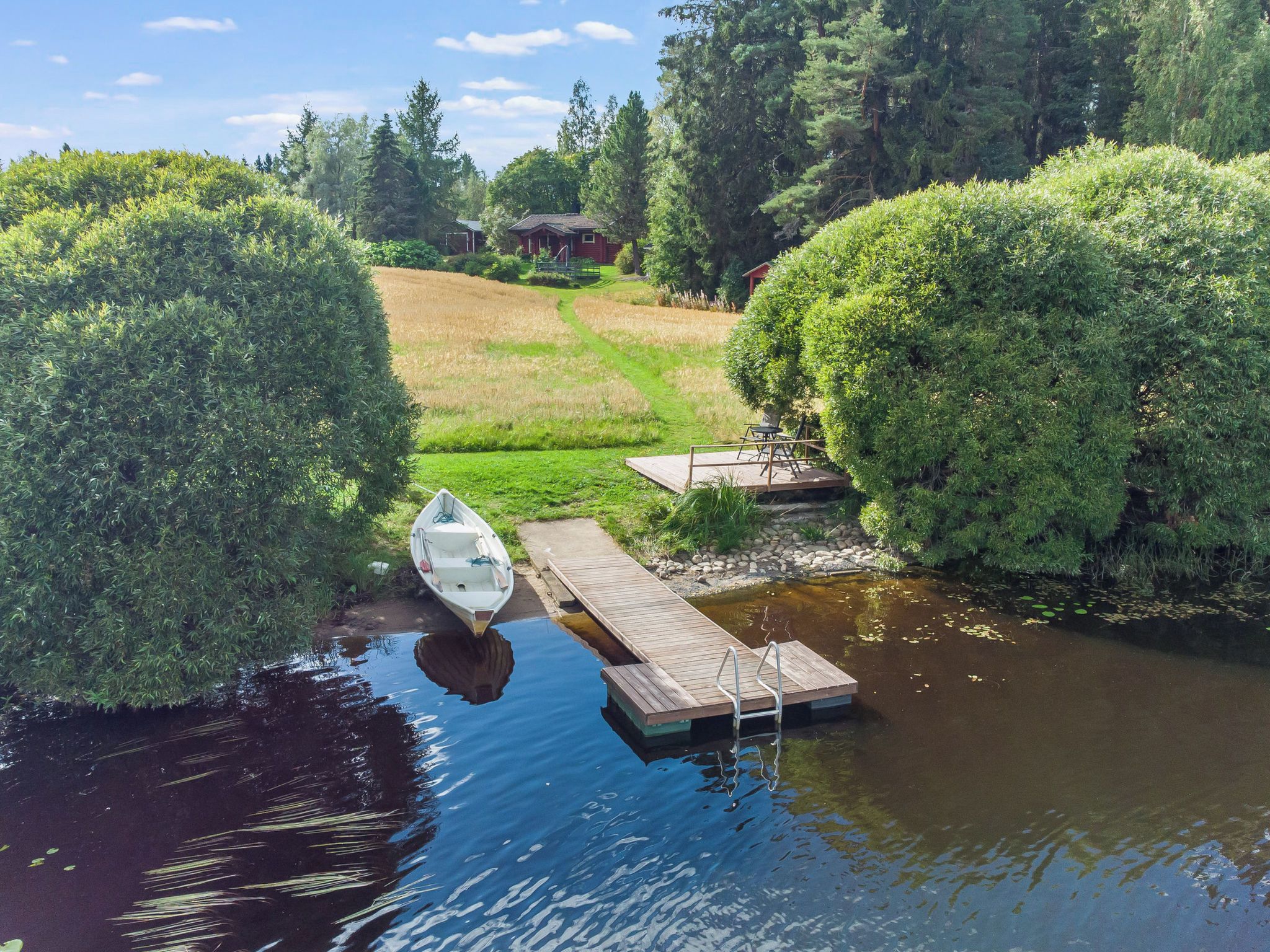 Eine friedliche Flusslandschaft mit Steg, kleinem Boot und Holzterrasse.