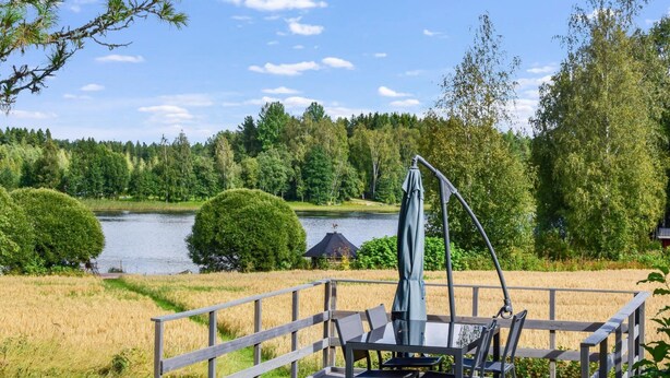 A wooden deck with a table and chairs, overlooking a lake and surrounded by trees. - Petäjäniemi by Interhome (Kinnula)