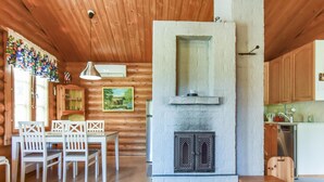 A cozy cabin interior with a dining area, a fireplace, wooden walls, and a kitchen. - Petäjäniemi by Interhome (Kinnula)