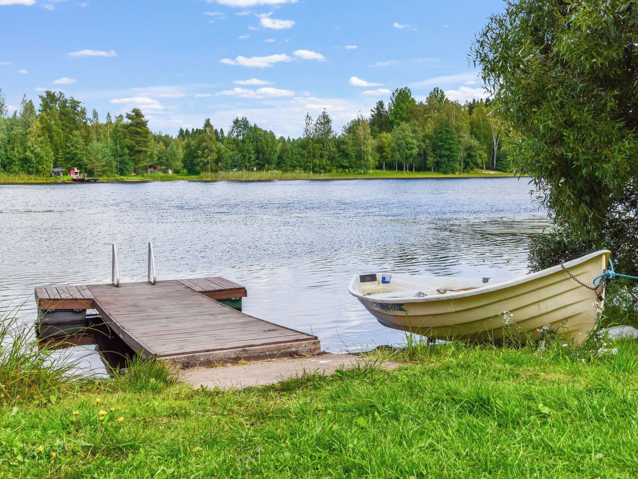 A calm lake with a wooden dock and a boat tied to it.