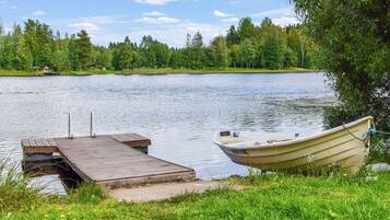 A calm lake with a wooden dock and a boat tied to it.