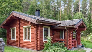 A log cabin with a porch, a chimney, and a small garden area. - Petäjäniemi by Interhome (Kinnula)