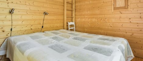 Een houten kamer met een bed, een stoel en een plank.