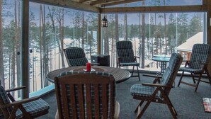 Ett rum med ett stort fönster med utsikt över ett snötäckt landskap, inrett med flera stolar och ett bord.