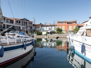 A marina with boats docked, a bridge in the background, and buildings with traditional architecture.
