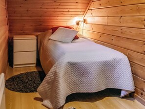 Um quarto pequeno e acolhedor, com uma cama de solteiro, uma mesa de cabeceira e um criado-mudo.