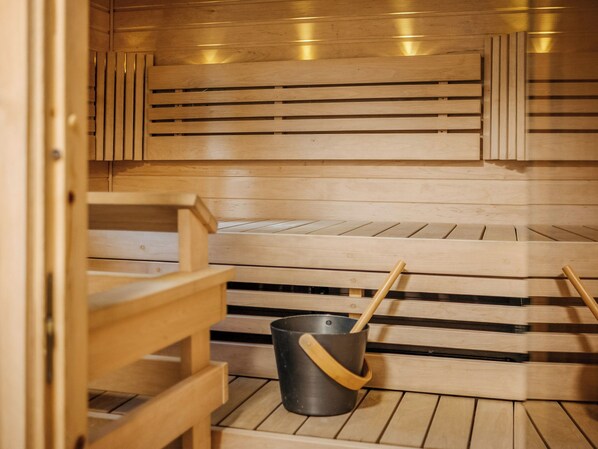 A sauna with wooden benches and a bucket with a wooden handle. - Levinstone by Interhome (Kittilä)