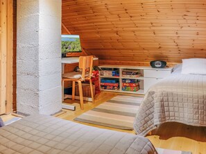Een gezellig slaapkamer op zolder met een schuine kap, houten wanden, een stapelbed, een bureau met een computer en een boekenkast.