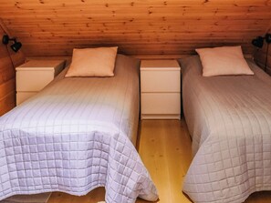 A room with two single beds, each with a pillow and a nightstand.