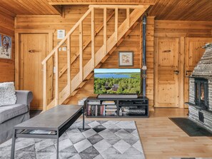 A wooden interior with a staircase, a television on a stand, a fireplace, and a couch. - Levinstone by Interhome (Kittilä)