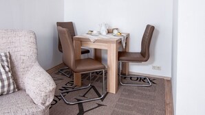 Een gezellig eethoekje met een houten tafel en vier stoelen, een decoratieve wandversiering en een vloerkleed met een geometrisch patroon.