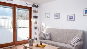 Een woonkamer met een bank, een houten salontafel en een glazen deur naar buiten.