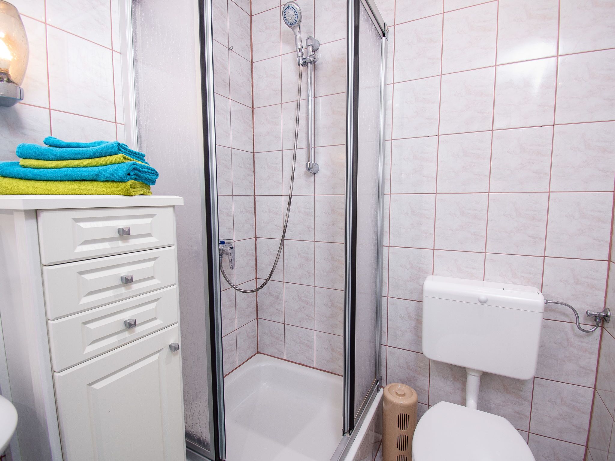 Une salle de bain avec une douche, des toilettes et un meuble contenant des serviettes pliées.