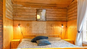 A wooden-paneled room with a bed, bedside lamps, and a painting on the wall.