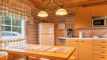 Una cucina accogliente con mobili in legno, un frigorifero, un forno a microonde e una finestra vista alberi.